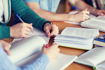 Image showing close up of hands with books writing to notebooks