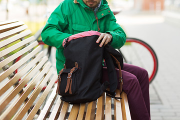 Image showing close up of man with backpack on city bench