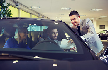 Image showing happy couple with car dealer in auto show or salon