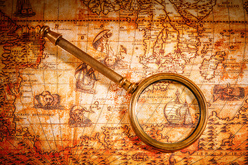 Image showing Vintage magnifying glass lies on an ancient world map