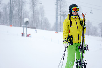 Image showing Female skier standing with skies in one hand on background beautiful mountain landscape