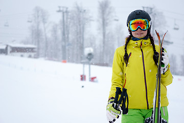 Image showing Female skier standing with skies in one hand on background beautiful mountain landscape