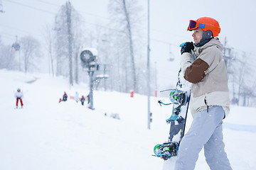 Image showing Men snowboarder standing with snowboard and looking at beautiful mountain landscape