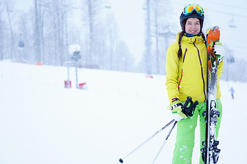 Image showing Female skier standing with skies in one hand on background beautiful mountain landscape