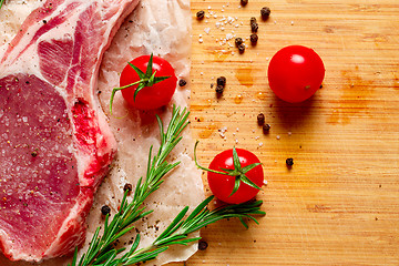 Image showing Pieces of crude meat with rosemary and tomatoes.