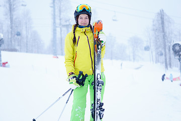 Image showing Female skier standing with skies in one hand on background beautiful mountain landscape