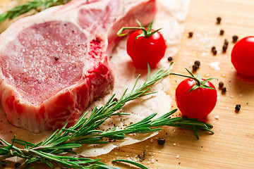 Image showing Pieces of crude meat with rosemary and tomatoes.