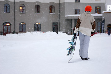 Image showing Taired man snowboarder with snowboard in one hand coming back in hotel.