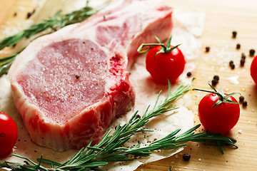 Image showing Pieces of crude meat with rosemary and tomatoes.