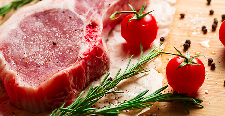 Image showing Pieces of crude meat with rosemary and tomatoes.