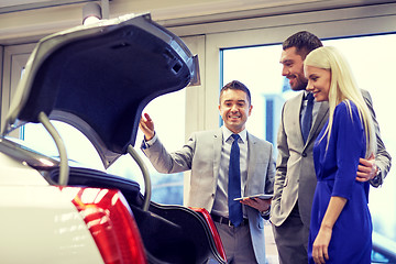 Image showing happy couple with car dealer in auto show or salon