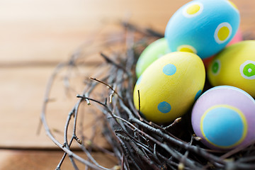 Image showing close up of colored easter eggs in nest on wood