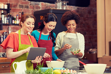 Image showing happy women with tablet pc cooking in kitchen