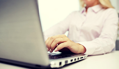 Image showing smiling businesswoman or student typing on laptop