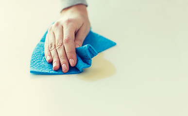 Image showing close up of hand cleaning table surface with cloth