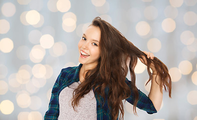 Image showing happy teenage girl holding strand of her hair