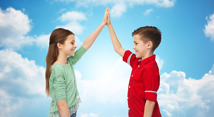 Image showing happy boy and girl making high five over blue sky