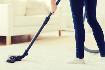 Image showing close up of woman legs with vacuum cleaner at home