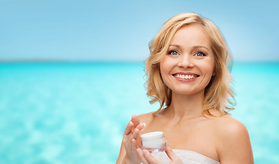 Image showing happy middle aged woman with cream jar over sea