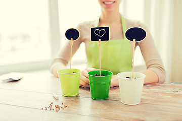 Image showing close up of woman over pots with soil and signs