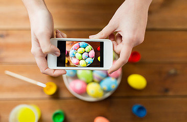 Image showing close up of hands with easter eggs and smartphone