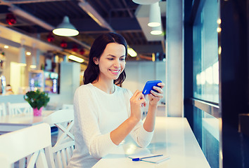 Image showing smiling woman with smartphone at cafe