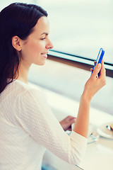 Image showing smiling woman with smartphone and coffee at cafe