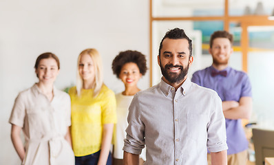 Image showing happy young man over creative team in office