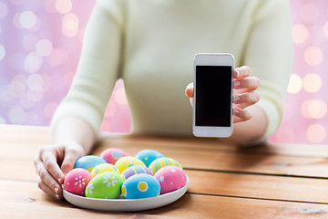 Image showing close up of hands with easter eggs and smartphone