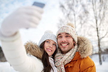 Image showing happy couple taking selfie by smartphone in winter