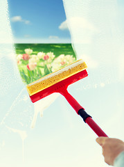 Image showing close up of hand cleaning window with sponge