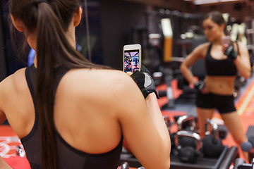 Image showing woman with smartphone taking mirror selfie in gym