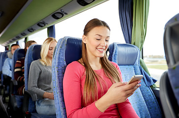 Image showing happy woman sitting in travel bus with smartphone