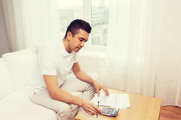 Image showing man with papers and calculator at home