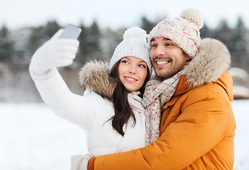 Image showing happy couple taking selfie by smartphone in winter