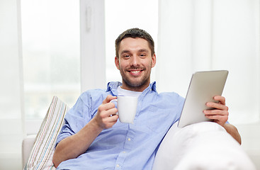 Image showing smiling man with tablet pc drinking tea at home