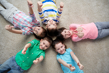 Image showing happy kids lying on floor and showing thumbs up