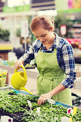 Image showing happy woman with watering can in greenhouse