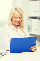 Image showing smiling businesswoman with clipboard in office