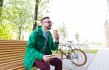 Image showing happy hipster man eating sandwich with coffee