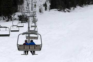 Image showing Two skiers on chair-lift in gray day