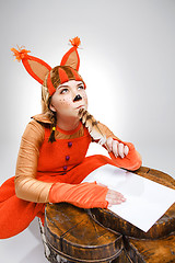 Image showing Young woman in image of squirrel writing with quill pen
