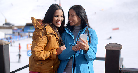 Image showing Two smiling young women checking a phone