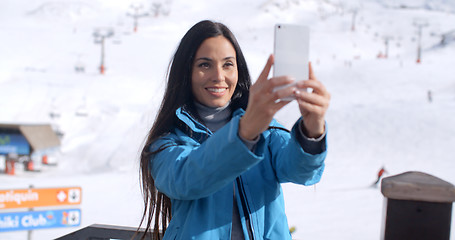 Image showing Smiling young woman taking a winter selfie