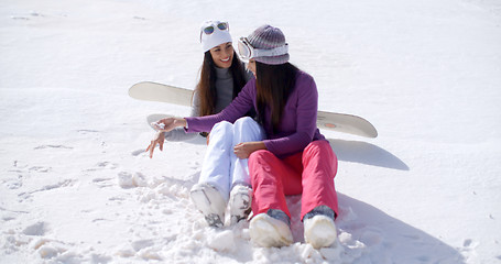 Image showing Two young women sitting chatting in the snow