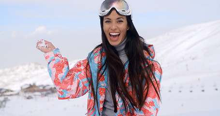 Image showing Laughing young woman throwing a snowball