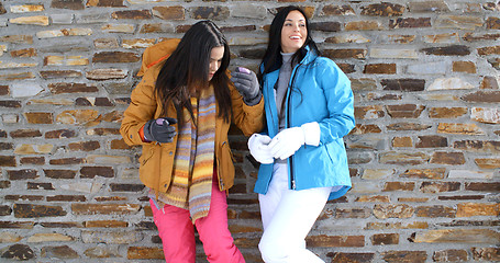 Image showing Cute twins in winter coats leaning on wall