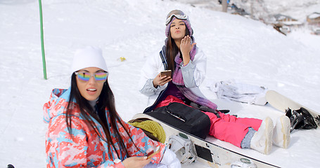 Image showing Two attractive women snowboarders relaxing