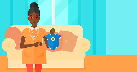 Image showing Pregnant woman with clothes for baby.