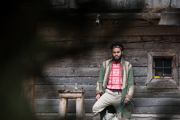 Image showing hipster with dog in front of wooden house